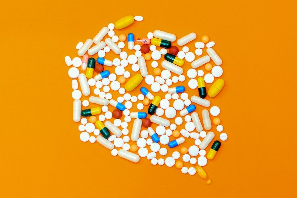 Several pills and tablets on an orange background.