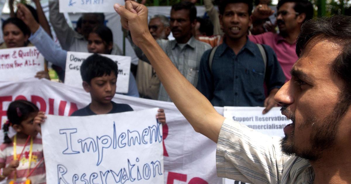 Several persons at a protest holding up signs and raising slogans related to reservations.