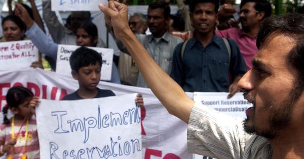 Several persons at a protest holding up signs and raising slogans related to reservations.
